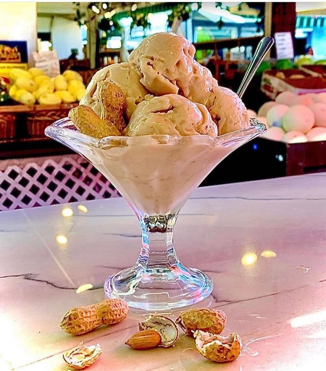 A tall glass of scoops with nuts scattered on the counter.