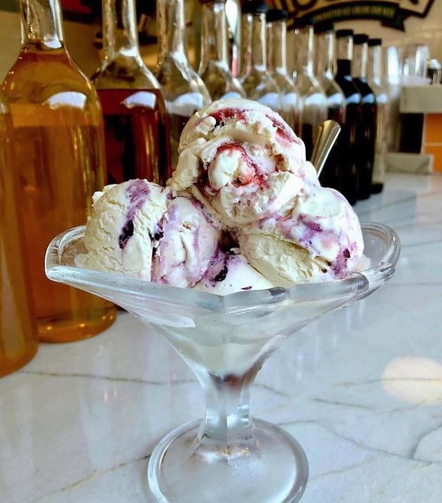 A coupe of scoops with the syrup bottles behind.