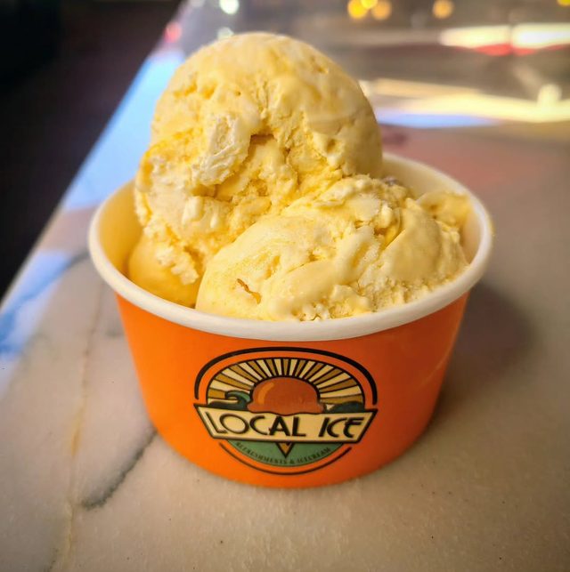 An orange Local Ice cup filled with pale yellow ice cream.
